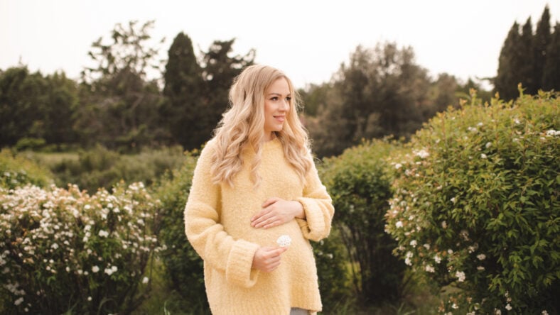 Pregnant woman wearing knitted sweater over nature